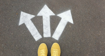 Woman,Standing,Near,Arrows,On,Asphalt,,Top,View.,Choice,Concept