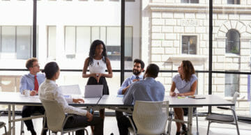 A shutterstock image of a woman leading a meeting in a meeting room